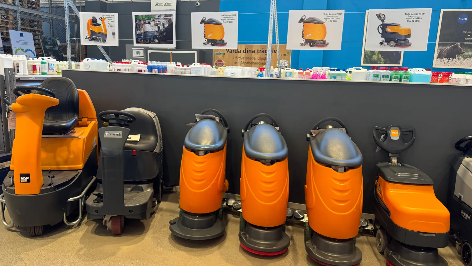 Rad av orange Taski Swingo-skurmaskiner uppställda i Qtronics lokal